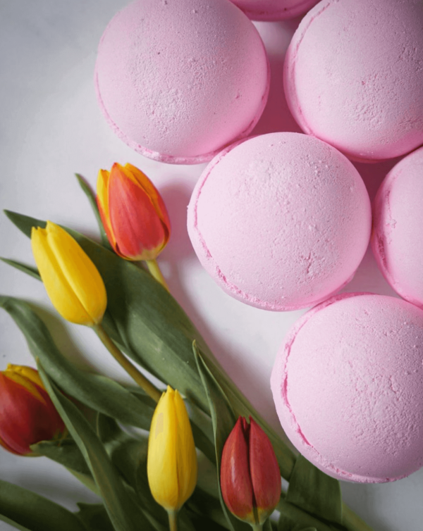 set of pink bath bombs displayed next to flowers